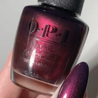 A bottle of nail polish being held by a hand.