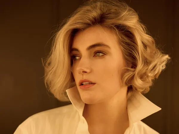 A blonde model wearing a white Oxford shirt