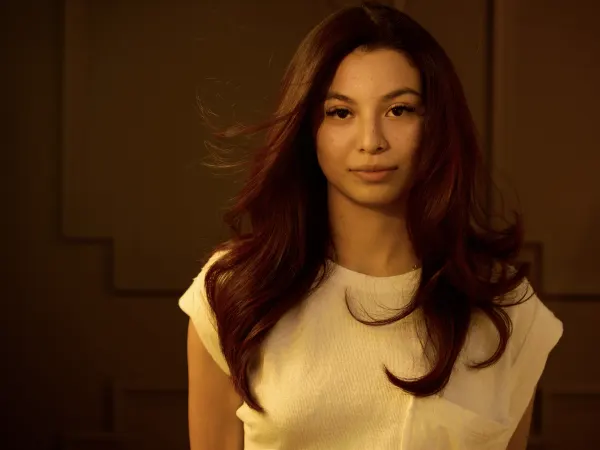 A model with long red hair wearing a white blouse