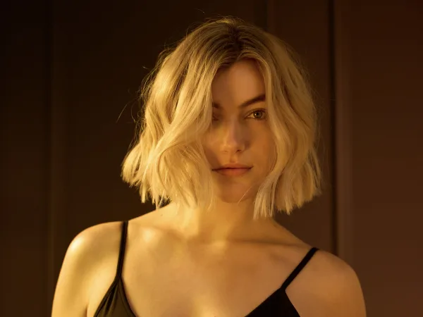 A woman with a mid-length blonde bob in a black slip dress