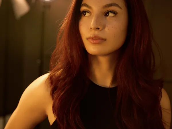 A model with long red hair looks sideways