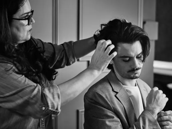 A hairdresser works on a male model's hair