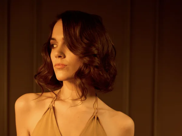 A model with brunette hair in a short chignon looks sideways