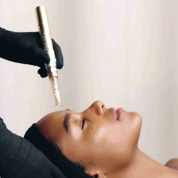 Hand using the SkinStylus microneedling device with a client during a facial