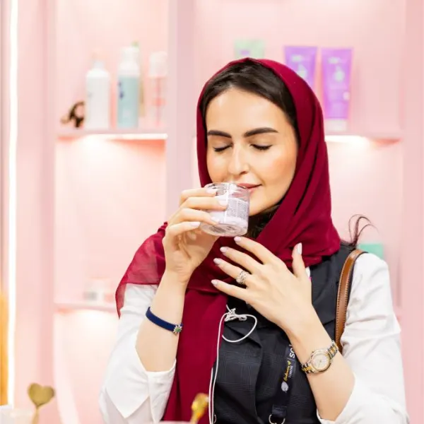 Woman holding a fragrance tester strip and smelling perfume at Beautyworld Middle East 2025.