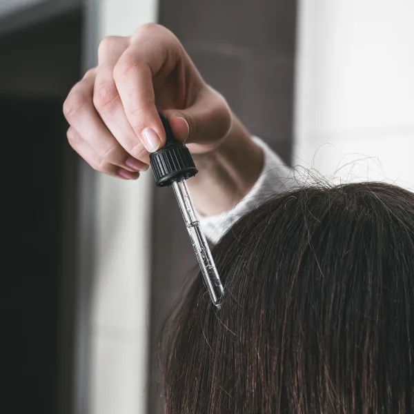 the rear view of a head of hair, having serum dropped onto the scalp.