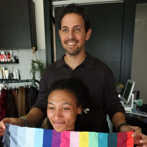 A man holds a piece of fabric in front of a woman's face