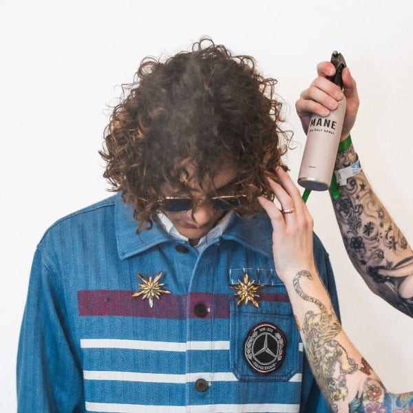 hands spraying a hair product into a man's hair