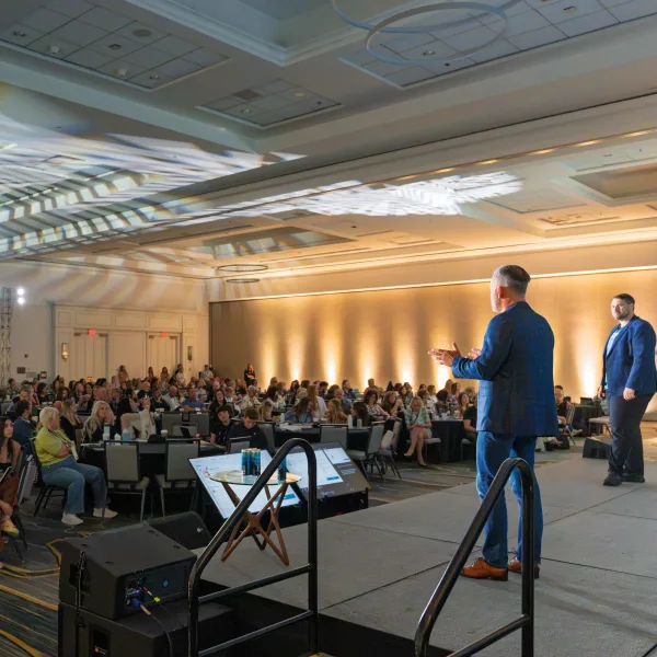 two men on a stage presenting to a crowd