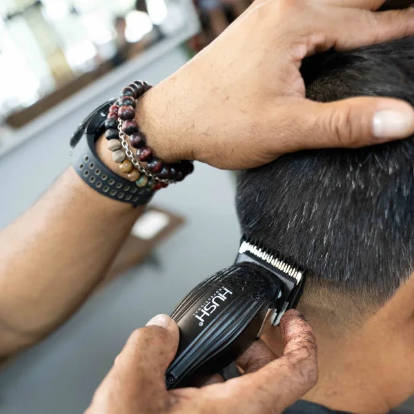 A barber holds a clippers and works on a client's neck