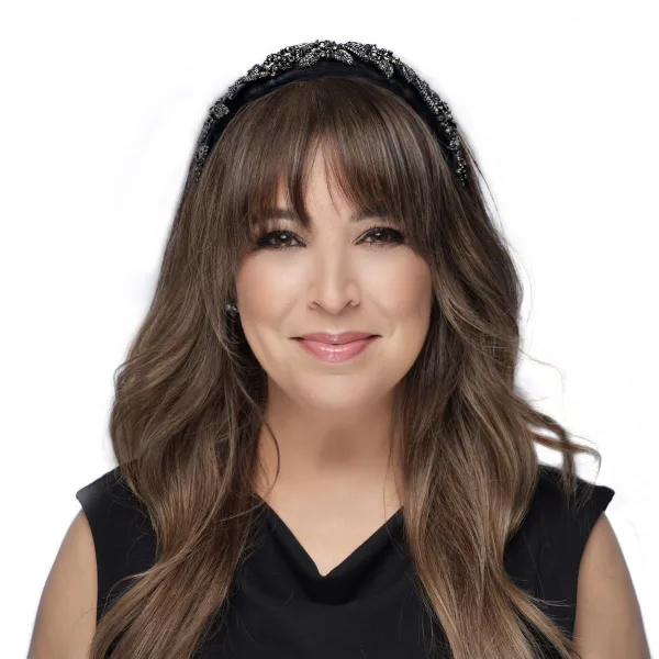 A woman with long brown hair, a black sleeveless blouse, and a beaded headband. 