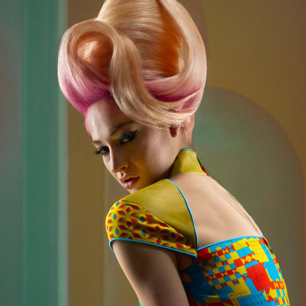 A model with a pink bouffant hairstyle in a multicolored shirt