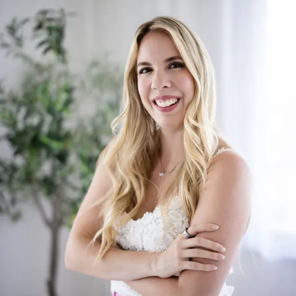 blonde woman smiling in a white tank top