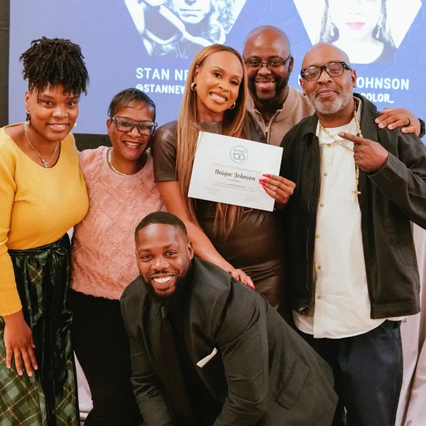 A group of people surround a woman receiving an award