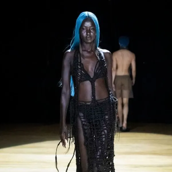 a fashion model with blue hair walking down a runway
