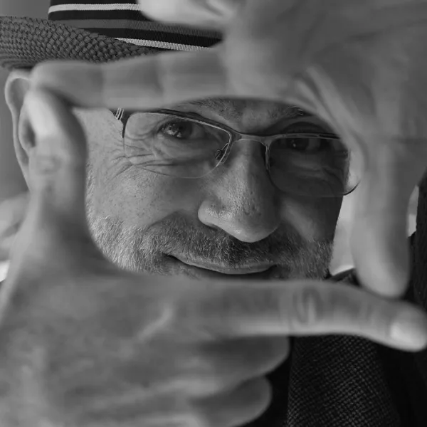 Daniel Cubillo, author of The Creative Masterind mind, peeks through his hands, resembling a television frame.