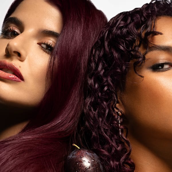 Two models with cherry red hair, one with long hair, one with shorter, curly hair.