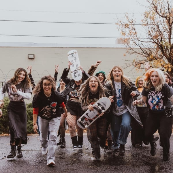 With skate boards in hand, a group of stylists playfully charge the photographer.