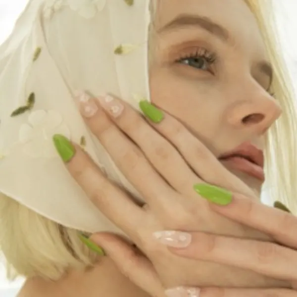 A young woman with blonde hair, a head scarf, and green nails.