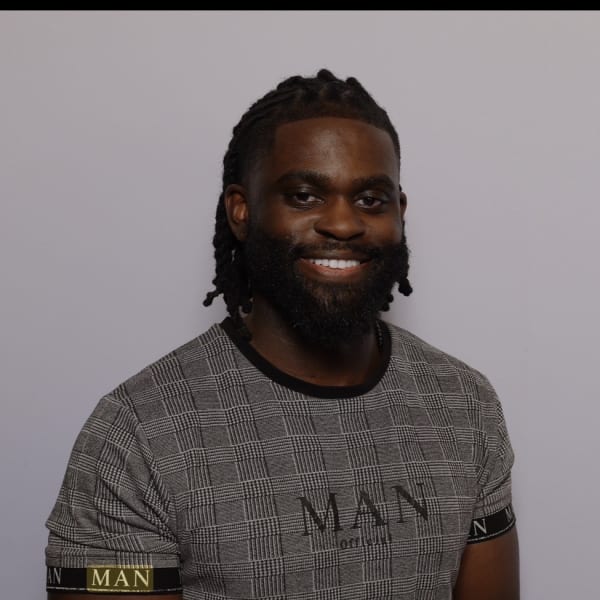 A man with dark hair and a beard, smiling.