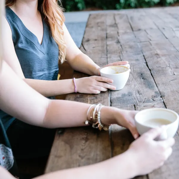 Two people holding cups. Only arms are visible.