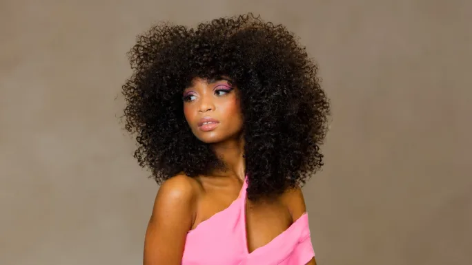 A woman in a pink top with a large natural texture afro
