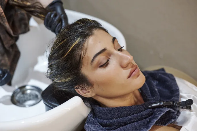 A woman has her head in the salon sink having her hair shampooed