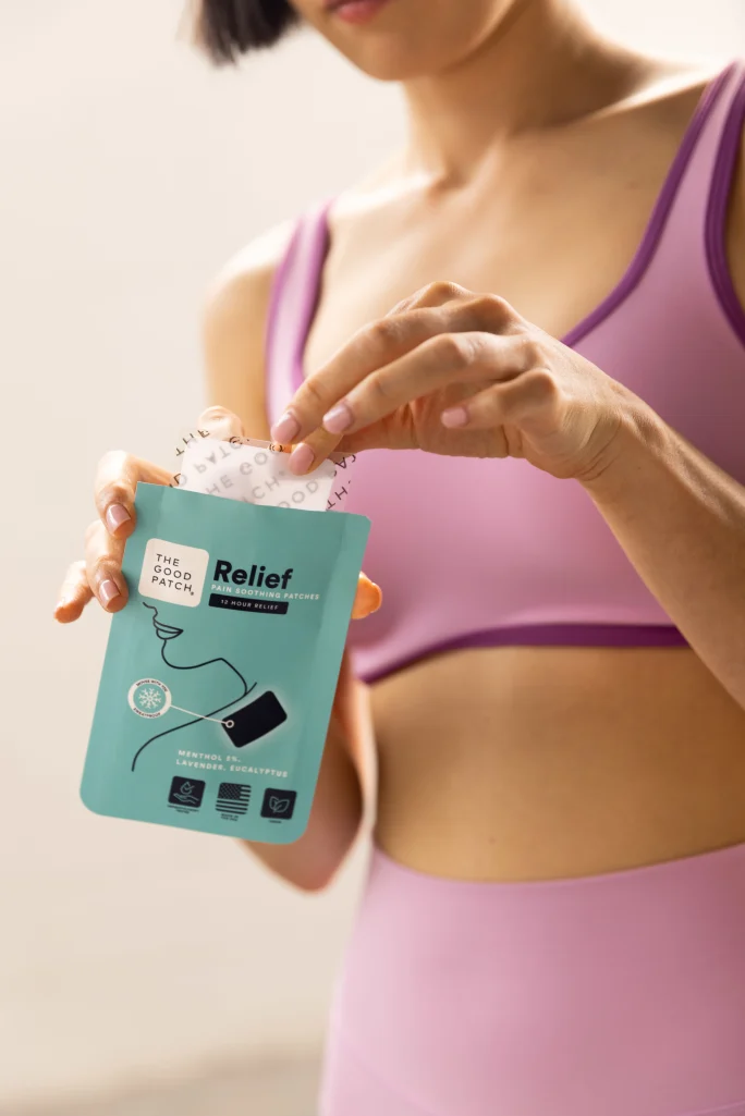 A woman in workout gear pulls out a patch from a package.
