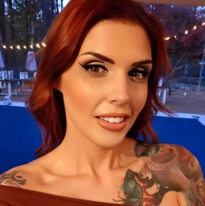 A woman with red hair and tattoos