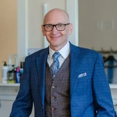 A bald white man wearing a suit and glasses