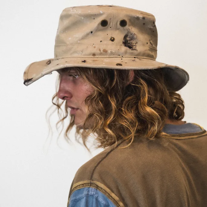 man with curly, shoulder length hair wearing a hat