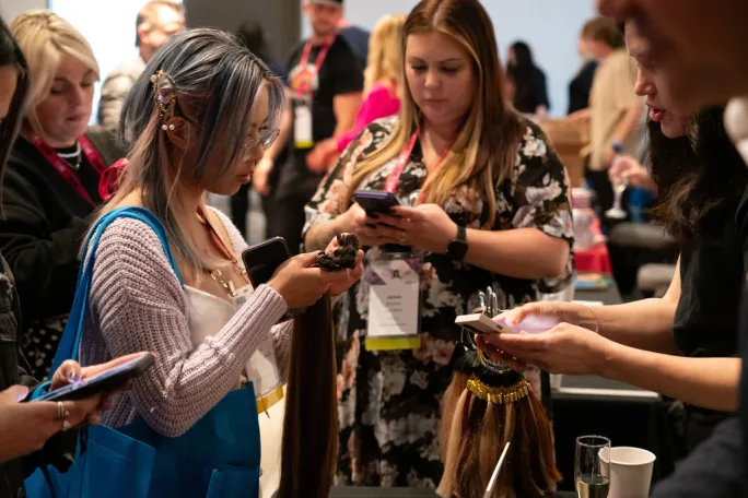 A circle of hairdressers look at their phones
