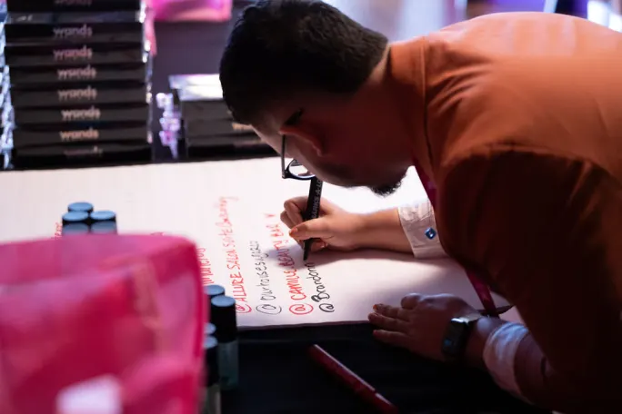 A man adds his name to a sheet of paper.