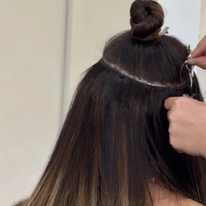 hands sewing extensions into hair