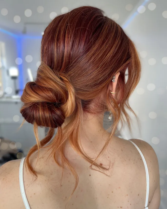 The back of a woman's head, showing red hair and a chignon.