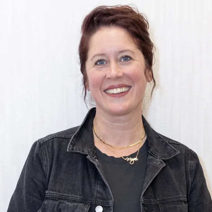 A smiling woman wearing a jean shirt. 