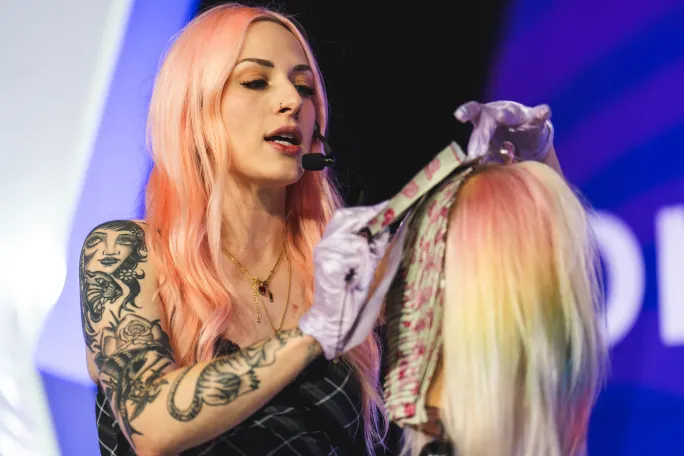 A hairdresser applies hair color on a mannequin head