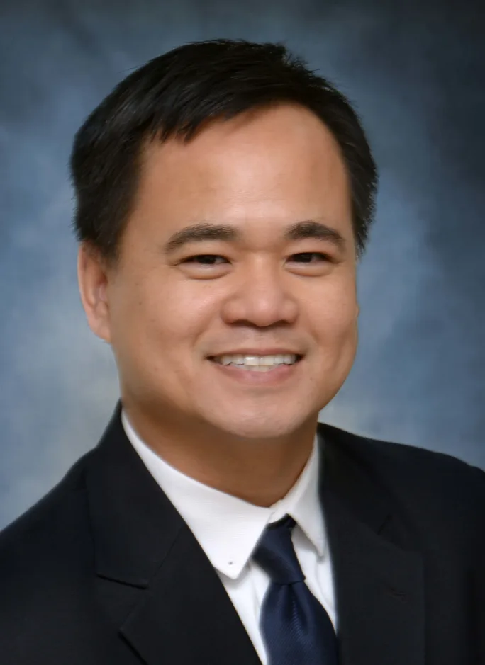 A man smiling and wearing a black suit
