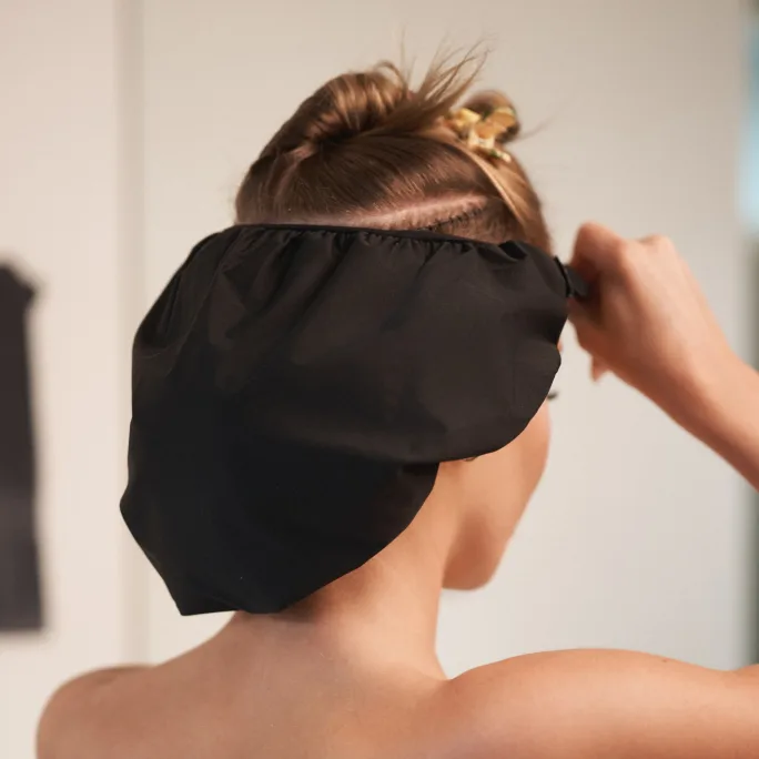 A woman putting on a shampoo cap
