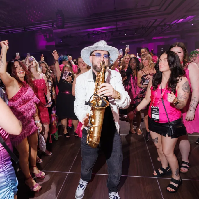a man playing saxophone in a dancing crowd