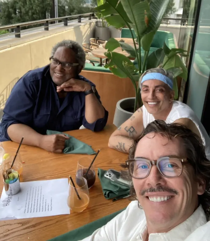 Three men pose for a picture at a restaurant table.