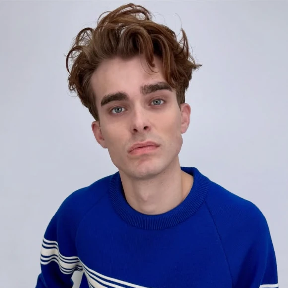 A young man in a blue sweater and lots of hair