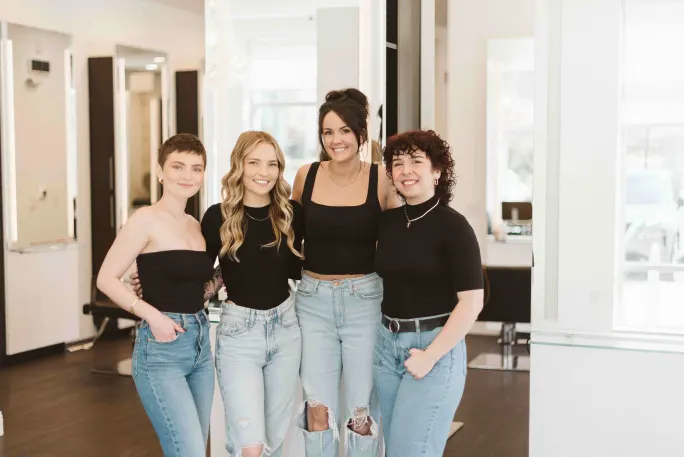Four stylists in black shirts and jeans pose for a picture.