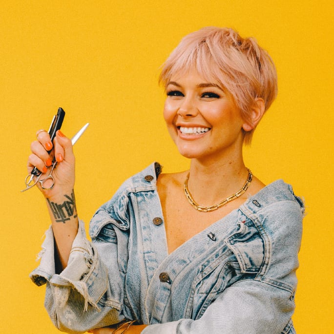 A smiling woman with short hair holding a razor.