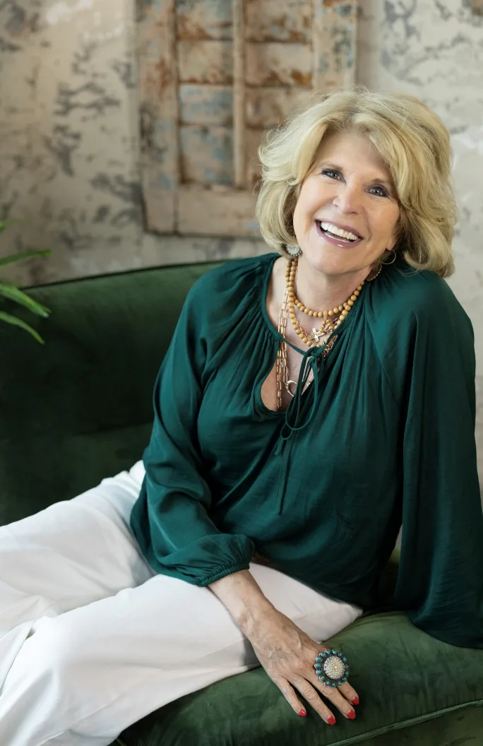 Kim Cloud poses in an emerald green top and white pants.