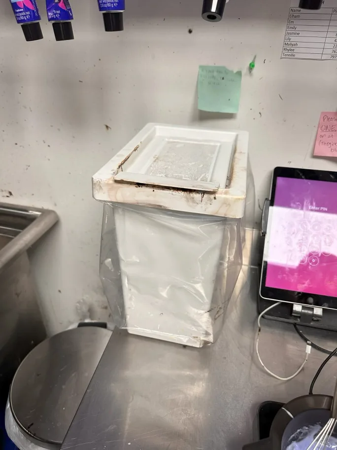 A small plastic trash bin in a color room