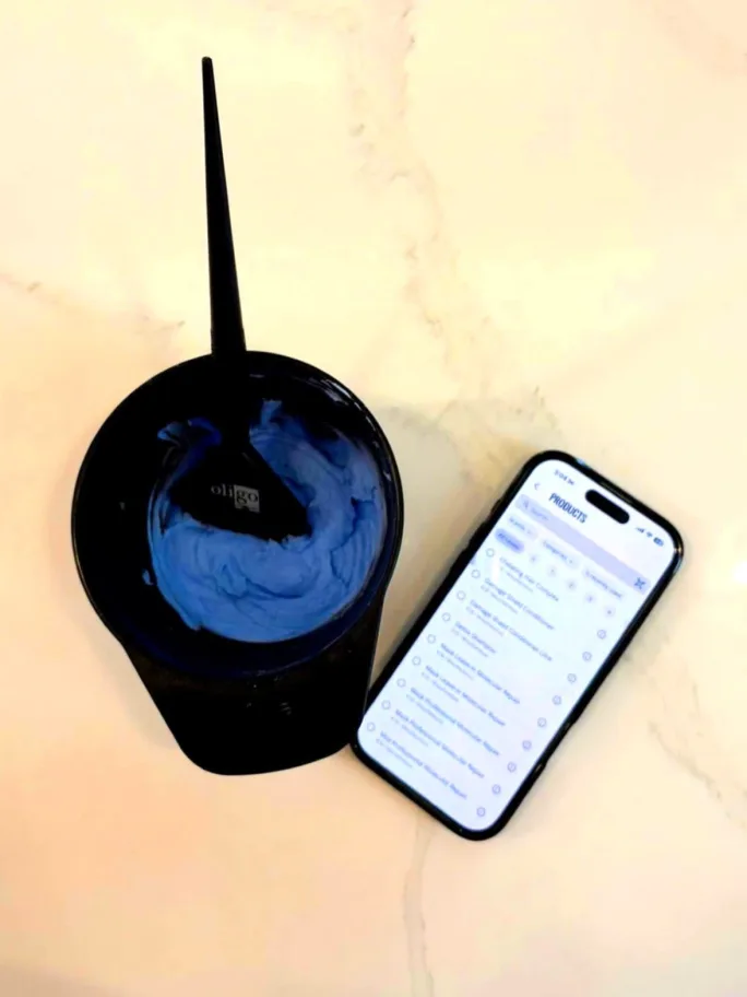 A bowl of a client's color formula next to a phone with the SalonScale app open at Shampoo Society in Whitby, Ontario. 