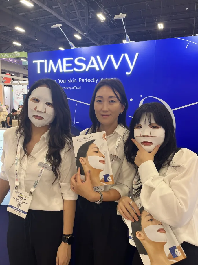 At the TimeSavvy booth at Cosmoprof North America, three women demonstrate face masks.