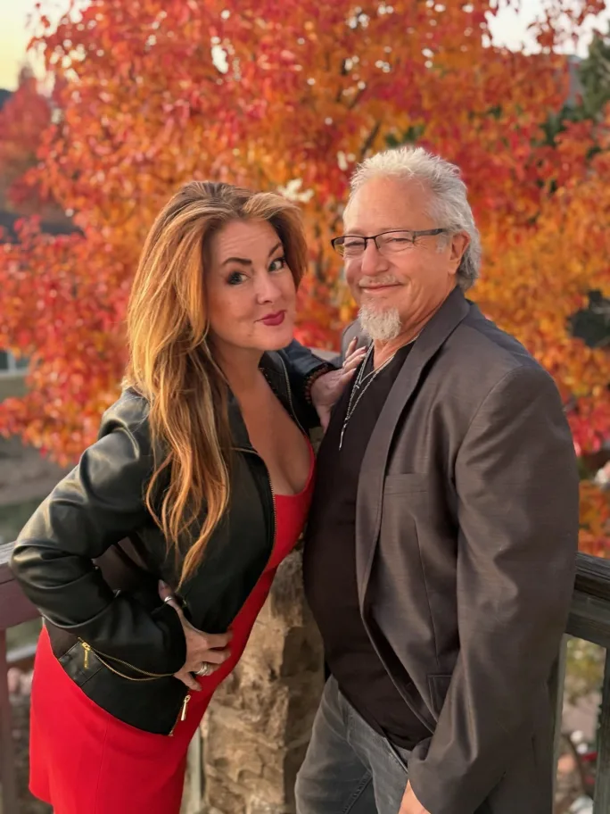 Posing in front of a colorful fall tree, Ame and Dennis Metcalfe, owners of D'Ametris in Broomfield, Colorado.