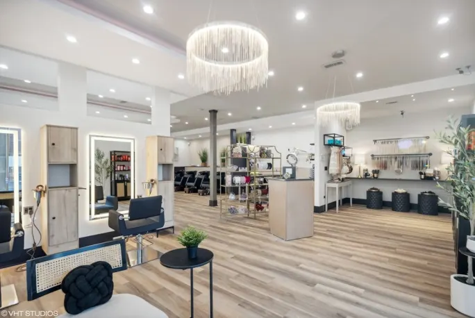 Chandeliers hang above an open concept salon with white oak floors.